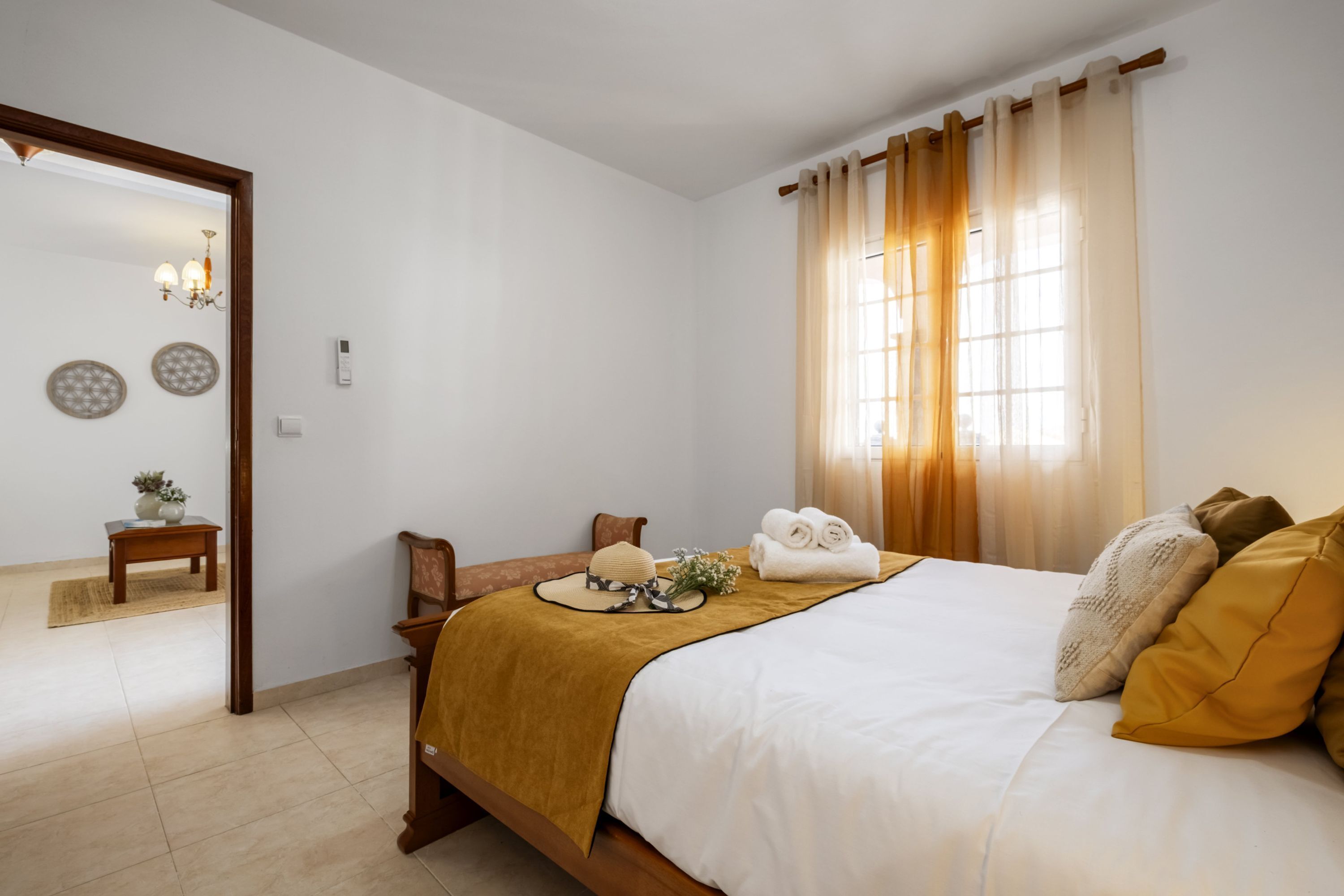 A bedroom with a bed, a wooden nightstand, a mirror, and a window with curtains.