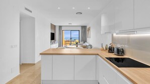 Eine moderne Küche mit weißen Schränken, einer Holz Arbeitsplatte und Blick ins Freie.