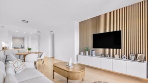 Ein modernes Wohnzimmer mit einer Couch, einem Couchtisch und einem Fernseher, der an einer Wand aus Holzpaneelen befestigt ist.