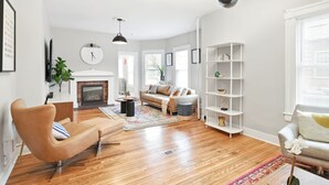 Un salon moderne avec un plancher en bois, un canapé beige, une table basse et une bibliothèque.