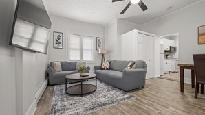 A modern living room with two grey sofas, a coffee table, and a dining table with chairs.