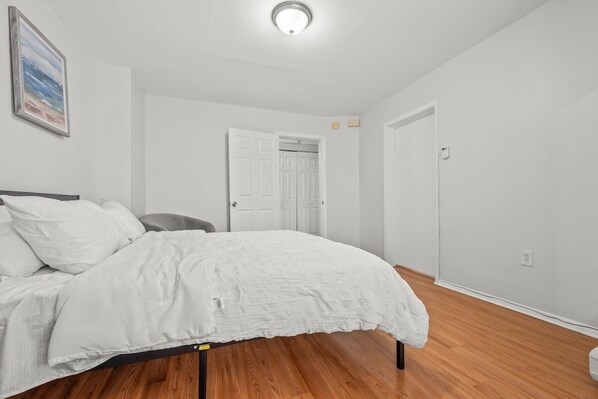 Un dormitorio con cama, una silla, una puerta y una lámpara.
