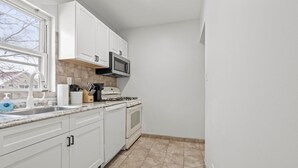 A kitchen with white cabinets, a microwave, a stove, and a sink.