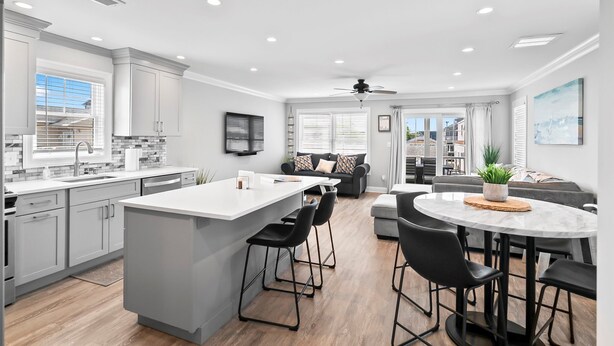 A modern kitchen with a central island, bar stools, and a dining area with a round table and chairs.