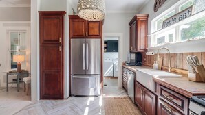 Una cocina moderna con armarios de madera, un refrigerador de acero inoxidable y un ventanal con un letrero que dice 'vamos a comer'.