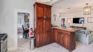 Una cocina moderna con un mueble grande de madera, un suelo con patrón de espiga y un área de comedor visible a través de un vano abierto.