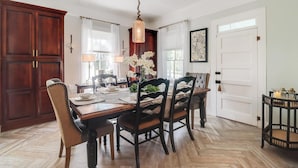Un comedor con una mesa de madera, sillas y una lámpara colgante.