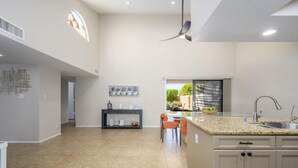 Une cuisine moderne dotée d’un plan de travail en granit, d’un évier en acier inoxydable et d’un ventilateur de plafond.