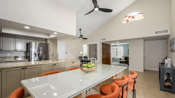 Une cuisine moderne dotée d’un îlot central, d’appareils électroménagers en acier inoxydable et de chaises orange.