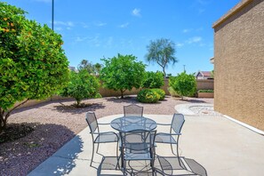 An outdoor patio with a round table and chairs, surrounded by gravel and greenery. - CASA EDEN/Luxury 3 BR Private Townhouse in Scottsdale (Scottsdale)