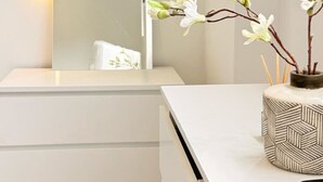 A minimalist room with a white desk, a wall-mounted mirror, a simple line drawing artwork, and a vase with white flowers. - Stylish apartment close to center zone 2, London, UK (London)
