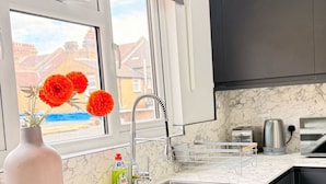 A modern kitchen with dark cabinets, a marble countertop, a stainless steel sink, and a window with a view of buildings. - Stylish apartment close to center zone 2, London, UK (London)