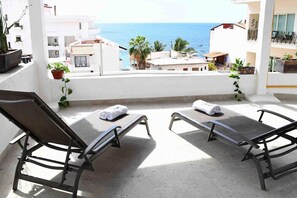 A balcony with two sun loungers, a potted plant, and a view of the sea. - Hacienda Vallarta - Los Muertos Beach (Puerto Vallarta)