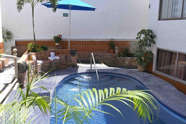A small outdoor hot tub with a stone wall and potted plants. - Hacienda Vallarta - Los Muertos Beach (Puerto Vallarta)