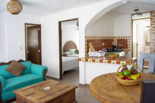 A living room with a turquoise sofa, a wooden coffee table, and a wicker fruit basket on a round table. - Hacienda Vallarta - Los Muertos Beach (Puerto Vallarta)