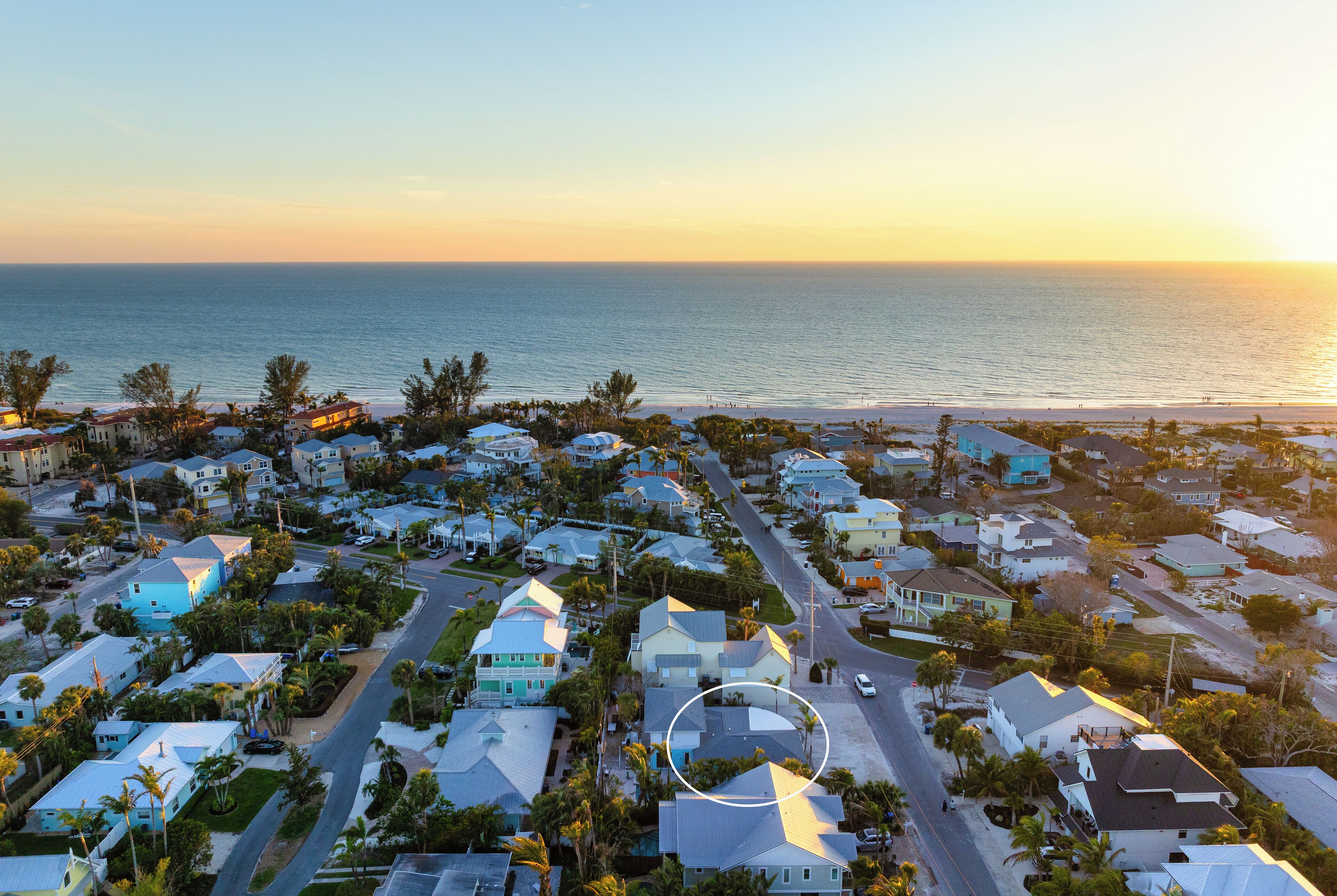 An aerial view of a coastal residential area with houses, roads, and a beach.
