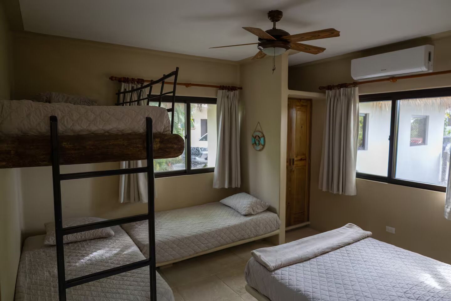 Une chambre de dortoir équipée de lits superposés, d’un ventilateur de plafond et d’un appareil de climatisation.