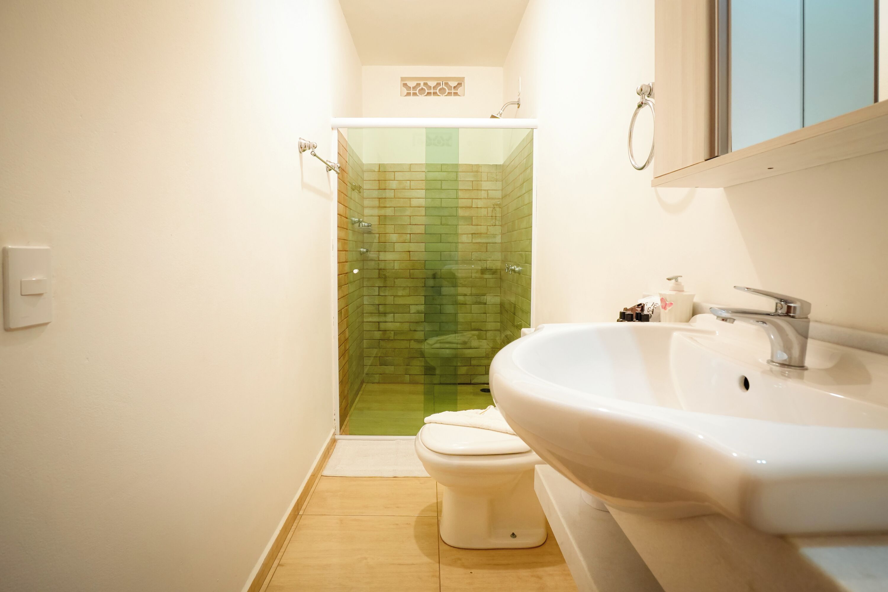 A bathroom with a glass-enclosed shower, a white toilet, and a white sink.