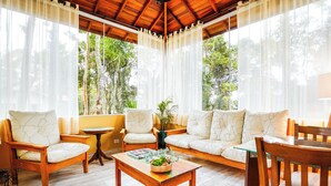 Una sala de estar acogedora con una mesa de centro de madera, dos sofás y sillones. Se observa una mesita redonda con una planta.
