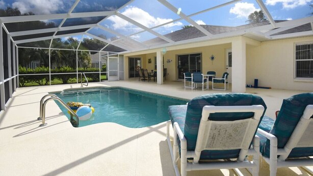 A covered swimming pool with lounge chairs and a patio area.