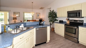 A modern kitchen with a granite countertop, stainless steel appliances, and white cabinetry.