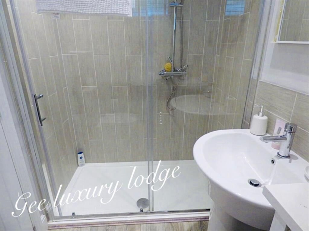 A bathroom with a glass-enclosed shower, a white sink, and a mirror.