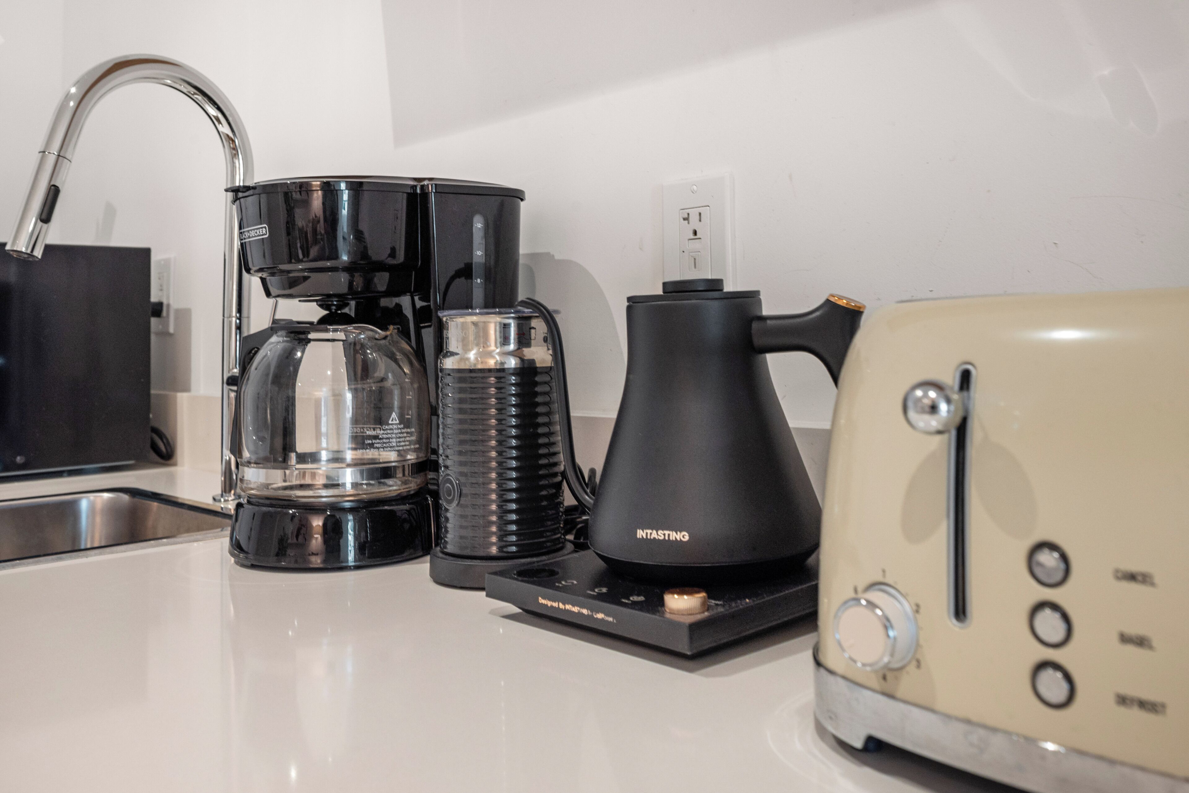Una cocina con cafetera, hervidor y tostadora sobre la encimera.