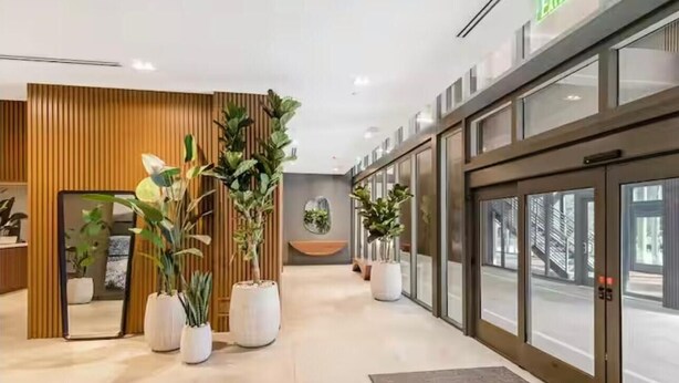 Eine moderne Hotelhalle mit Holzvertäfelung, Topfpflanzen und einem Glaselevator.