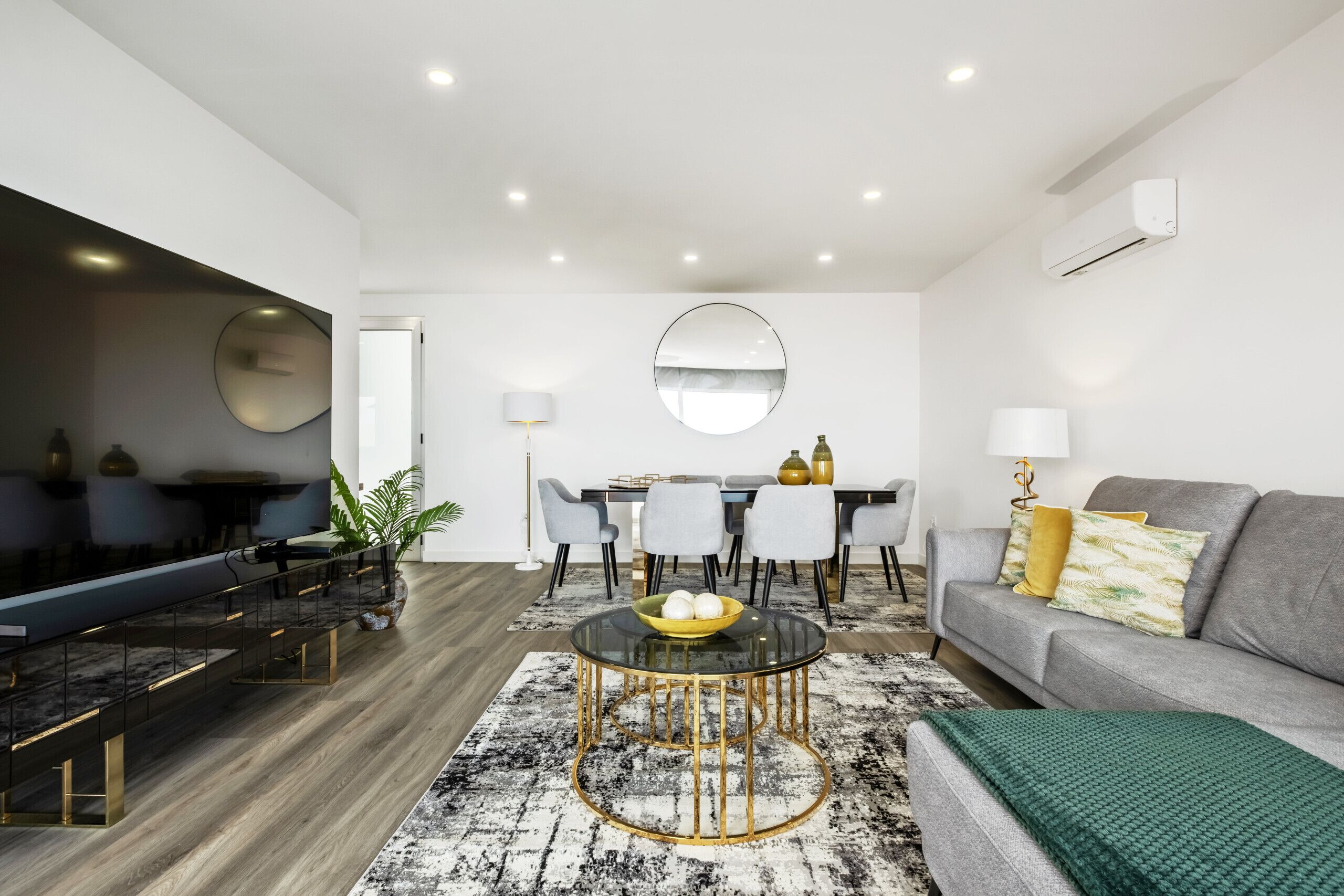 A modern living room with a dining area, a sofa, and a TV.