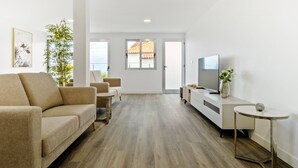 A modern living room with a sofa, a small table, a TV, and a plant. - Villa Vellure by Homie (Funchal)