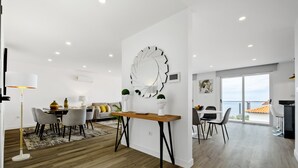 A modern living space with a dining area, a large decorative mirror, and a view of the sea. - Villa Vellure by Homie (Funchal)