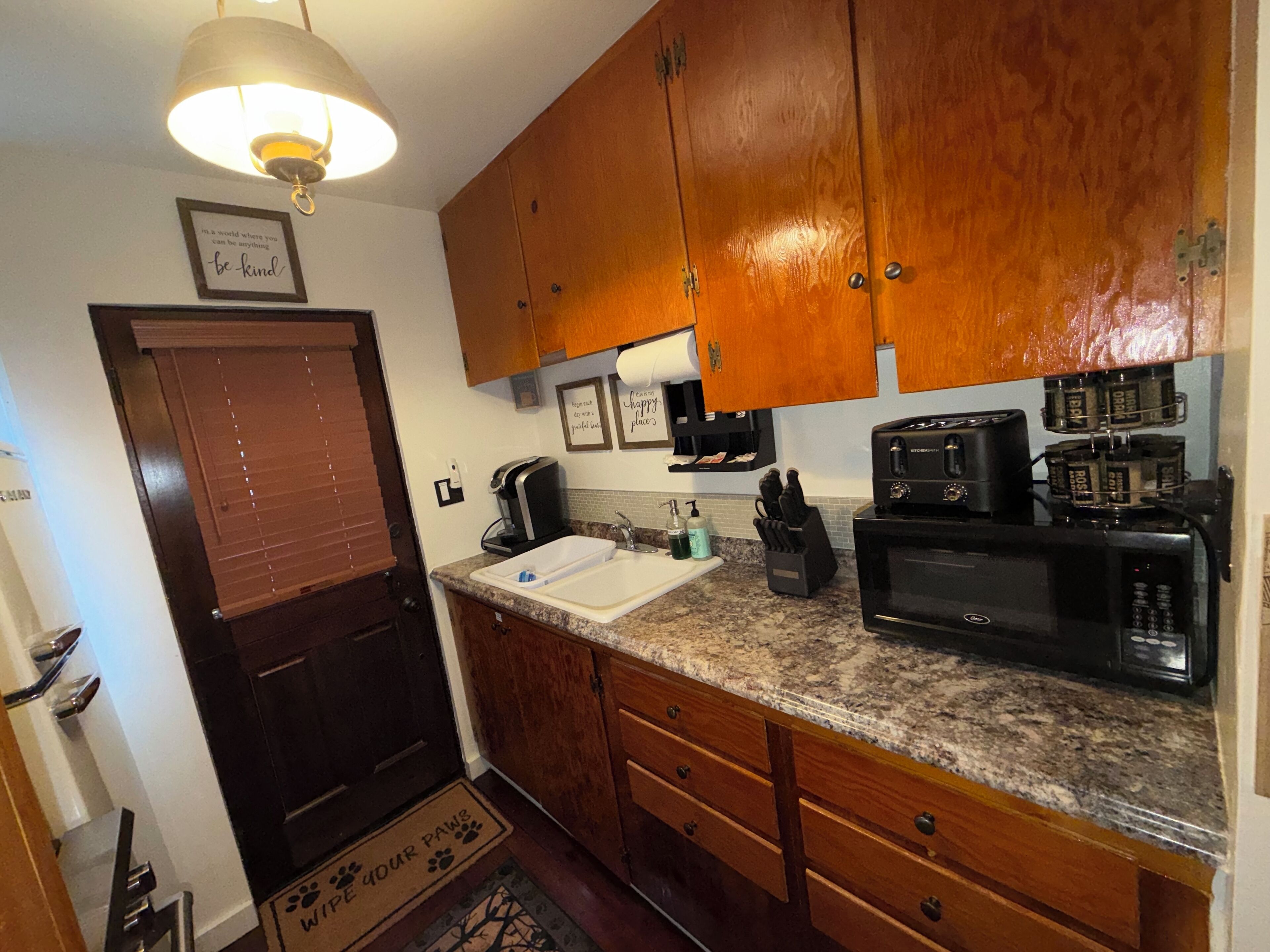 A kitchen with wooden cabinets, a built-in microwave, a coffee maker, and a sink.