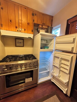 A kitchen with wooden cabinets, a gas stove, and a white refrigerator.