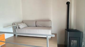 Ein modernes Wohnzimmer mit einer Couch, einer Holzbalkendecke, einem Kamin und einem Metallgeländer.