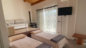A room with two beds, a bench, a TV, and a window with curtains. - Country house 5 minutes from downtown with garden and private parking space (Abruzzo)