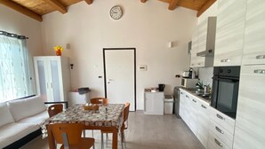 A cozy kitchen with wooden beams, a dining area with a table and chairs, and a white cabinet with a microwave. - Country house 5 minutes from downtown with garden and private parking space (Abruzzo)
