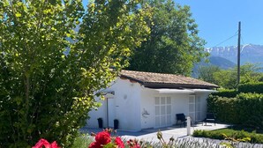 A white building with a tiled roof, surrounded by greenery and red flowers. - Country house 5 minutes from downtown with garden and private parking space (Abruzzo)