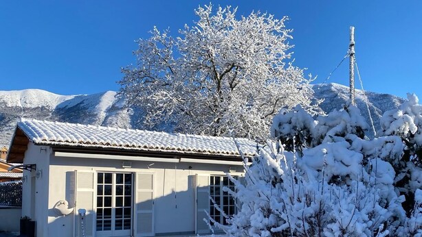 A building with a snow-covered roof, a garage, and a clear blue sky. - Country house 5 minutes from downtown with garden and private parking space (Abruzzo)