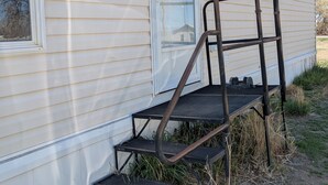 Une maison avec un escalier en métal menant à une porte.