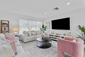 A modern living room with a sofa, coffee table, and pink armchair. - Jupiter Oasis • Heated Pool + Putting Green (Jupiter)