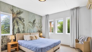 Une chambre à coucher avec un lit, des tables de chevet, une chaise et une fresque murale.