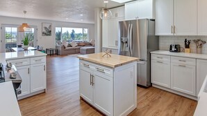 Una cocina moderna con armarios blancos, un refrigerador de acero inoxidable e una isla de madera.