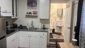 A modern kitchen with white cabinets, a stainless steel sink, and a wine-themed decoration.