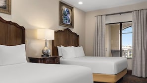 Une chambre d’hôtel avec deux lits, une table de chevet avec une lampe, une grande fenêtre avec des rideaux et un tableau encadré au mur.