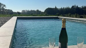 A pool with a champagne bottle and two glasses on a stone ledge. - Charming Provencal house with swimming pool and large garden (L'Isle-sur-la-Sorgue)