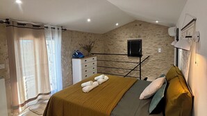 A bedroom with a bed, a dresser, a television, and a window with curtains. - Charming Provencal house with swimming pool and large garden (L'Isle-sur-la-Sorgue)