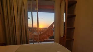 A hotel room with a bed, a view of the sunset through a window, and a hammock outside. - Casa Gostoso Mar (Monte Alegre)