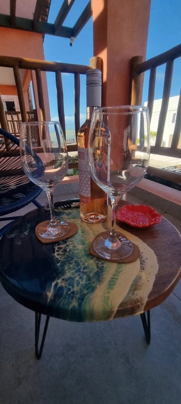 A table with two wine glasses and a bottle, set on a terrace with a view of the sea. - Casa Gostoso Mar (Monte Alegre)