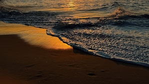 A sunset over a beach with waves gently lapping at the shore. - Casa Gostoso Mar (Monte Alegre)