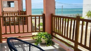 A balcony with chairs and potted plants, overlooking a beach. - Casa Gostoso Mar (Monte Alegre)